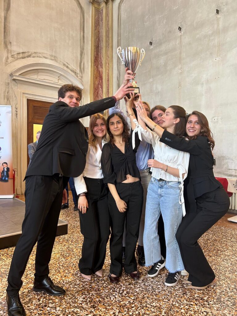 Squadra universitaria vincitrice che solleva il trofeo durante il Torneo di Dibattito Interuniversitario in una sala storica